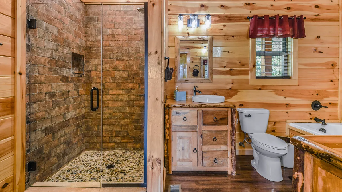 A luxurious bathroom with a free-standing soaking tub, spacious glass shower, and wood-paneled walls, creating an inviting and spa-like atmosphere. The space is designed for relaxation after a day of adventure.